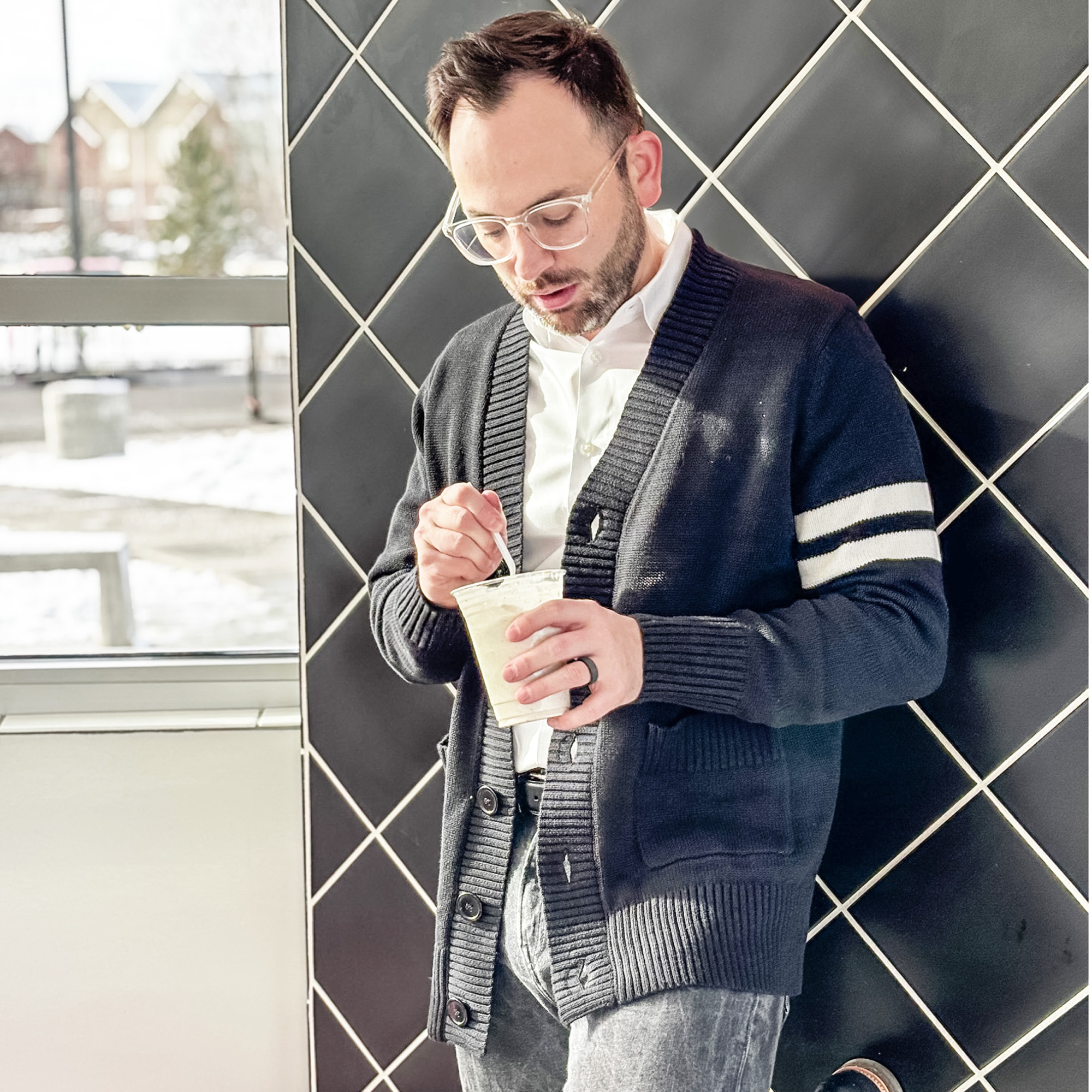 Mens Black Sweater Male standing in an ice cream shop wearing a black varsity letterman sweater eating ice cream.