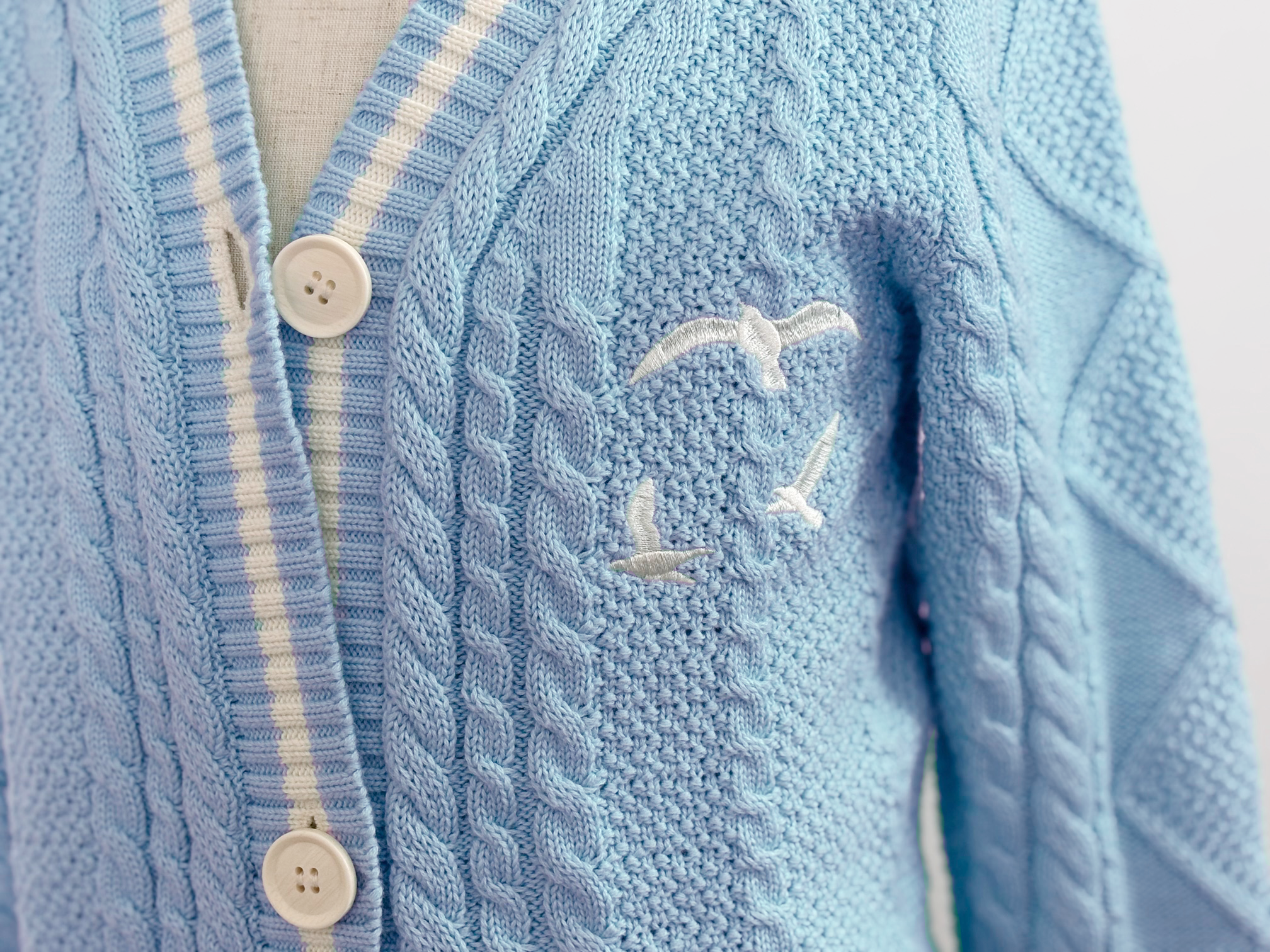 blue cardigan with white stripes and buttons and seagulls on the chest